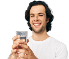 man holding a glass of water and smiling
