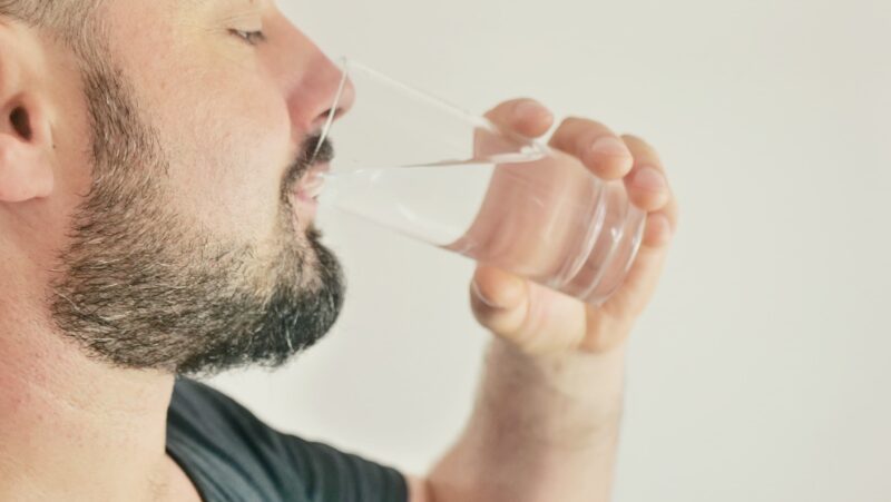 closeup of a man drinking softened and filtered water from environment water filtration