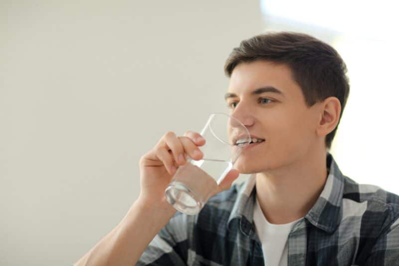 young man drinking water from a glass cup