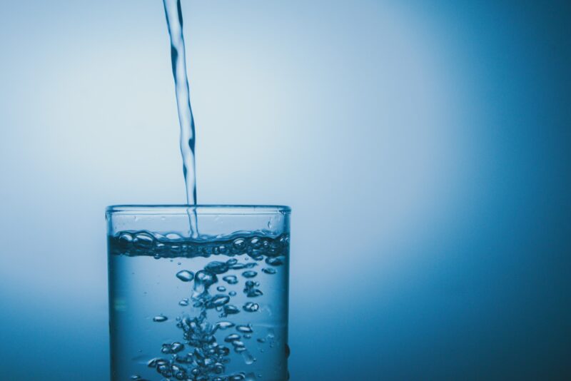 A glass of water on blue color background with copy space